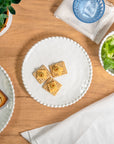 Cream colored, 8-inch round melamine salad plate, top view, with silverware, napkin, and blue tumbler on a wooden table