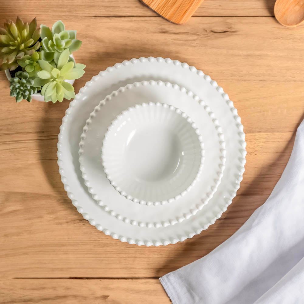 Cream colored, stacked melamine dinnerware set including 11-inch melamine dinner plate, salad bowl, and salad plate on a wooden table