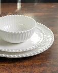 Cream colored, stacked melamine dinnerware set including 11-inch melamine dinner plate, salad bowl, and salad plate on a wooden table