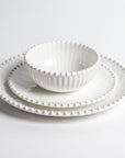 Stacked Merritt Designs Beaded Pearl melamine dinnerware set: salad bowl, salad plate, and dinner plate. Front view on white background