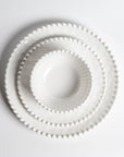 Stacked Merritt Designs Beaded Pearl melamine dinnerware set: salad bowl, salad plate, and dinner plate. Top view on white background